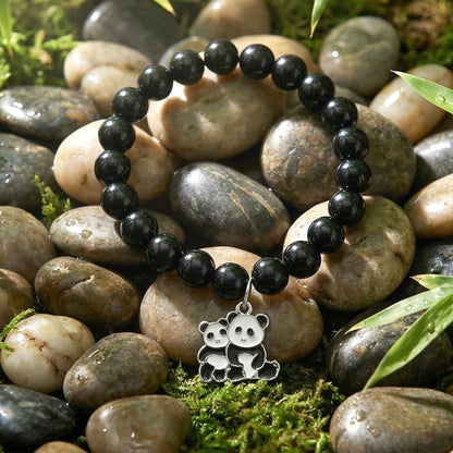Soft pastel bead bracelet on wrist with elastic band and black butterfly pendant