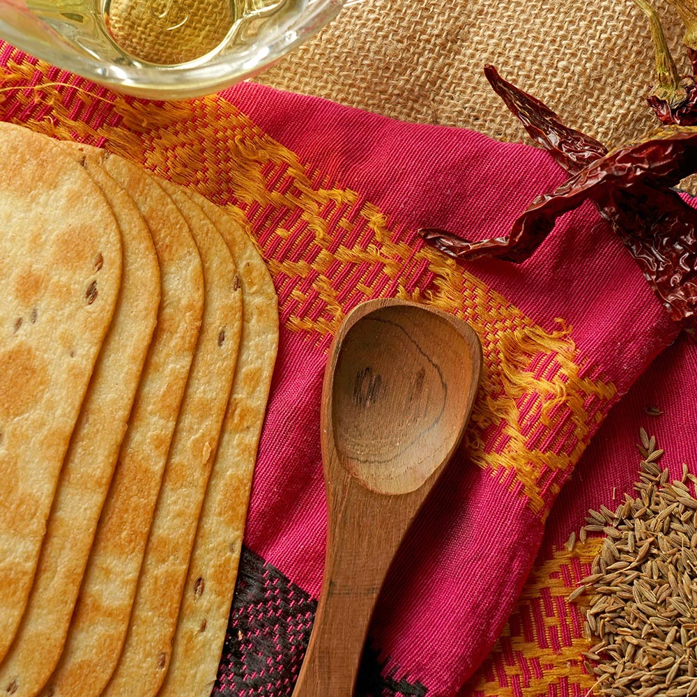 Hand holding a Maniarr's Ragi Diet Thin, highlighting its mini size and crispy texture.